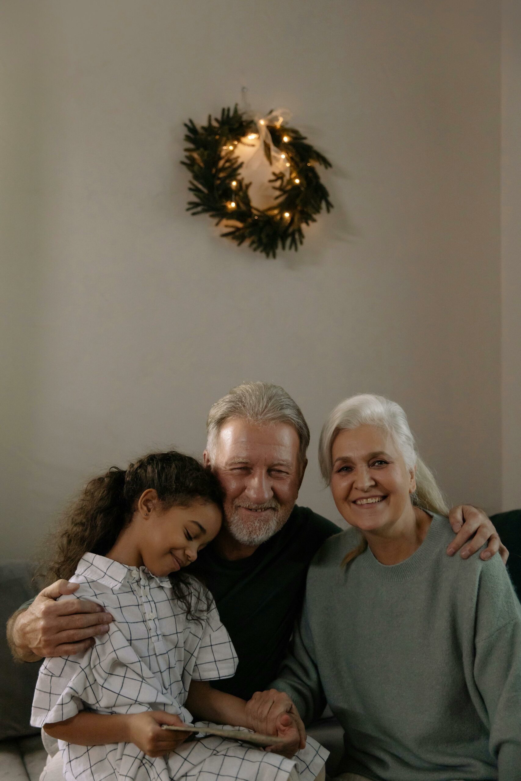 An elderly man and lady sitting on a sofa with a child