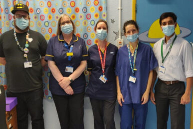 Group of unirome and plainly dressed medical colleagues with a backdrop of a colourful ward curtain