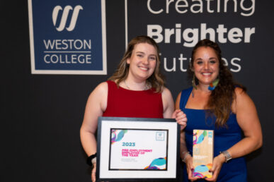 Photo of two Somerset NHS Foundation Trust Colleagues, dressed in evening wear, one person holding up an award and the other person holding up a certificate. The photo is of their upper body with a backdrop of Weston College logo and a slogan says Creating Brighter Futures