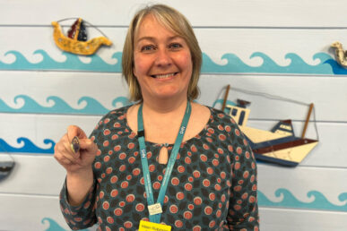 Neonatal physiotherapist Helen Robinson holding up her award for dedication to neonatal therapy education.