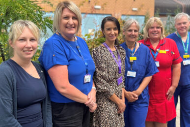 Five people stood in a line in their NHS uniform smiling