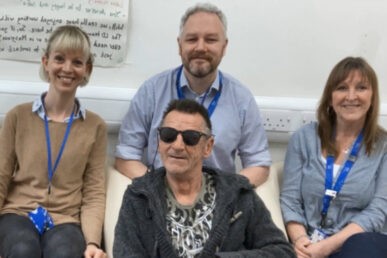 Three clinical colleagues sat together with a patient wearing sunglasses