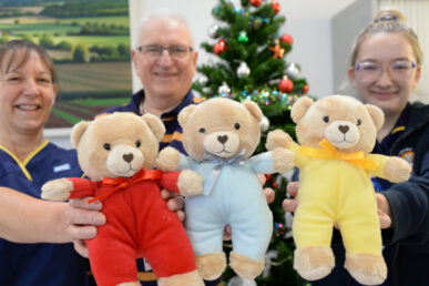 Three people holding colourful teddy bears